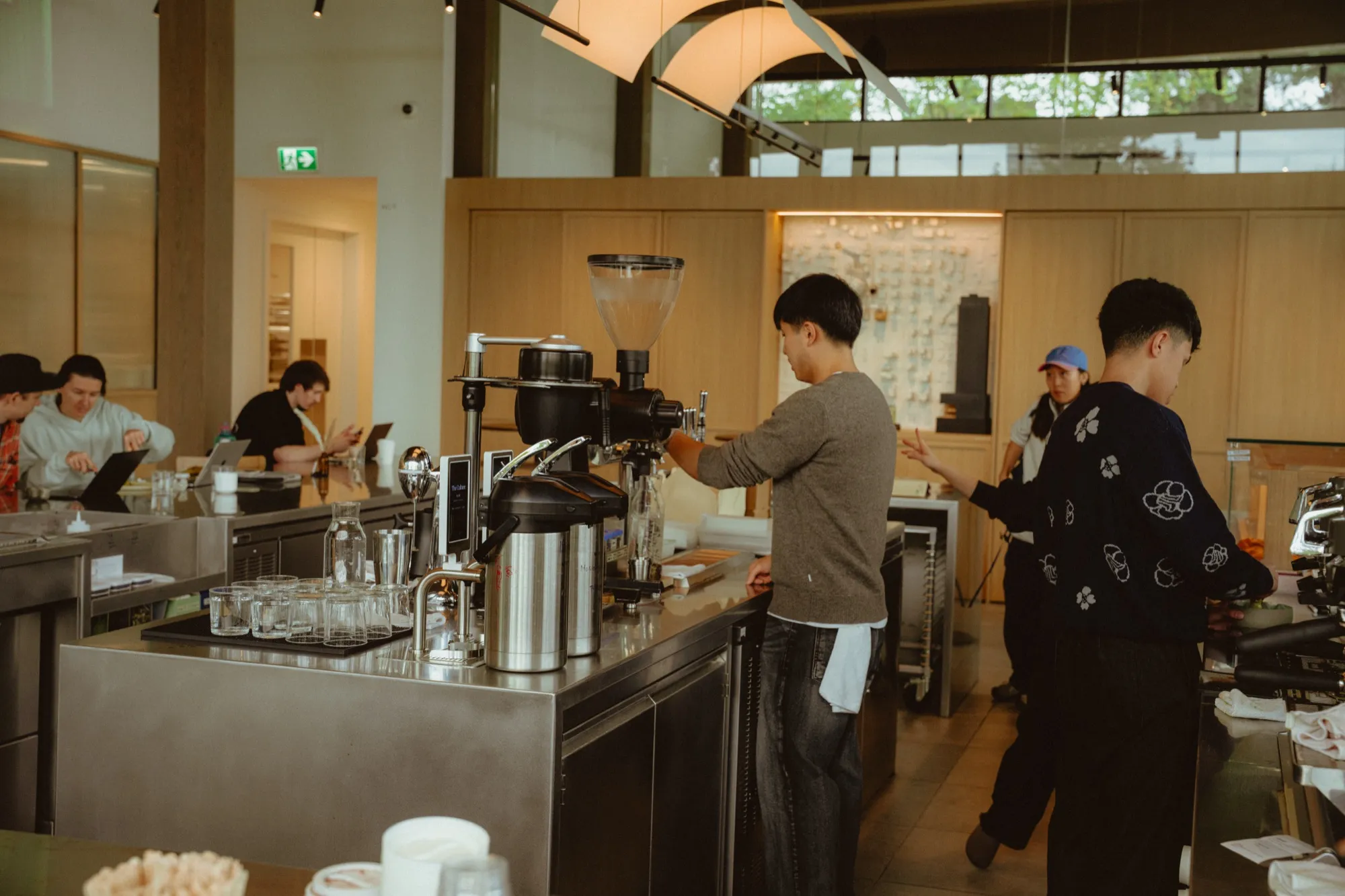 Baristas grinding coffee beans behind stainless steel counter in specialty Vancouver cafe