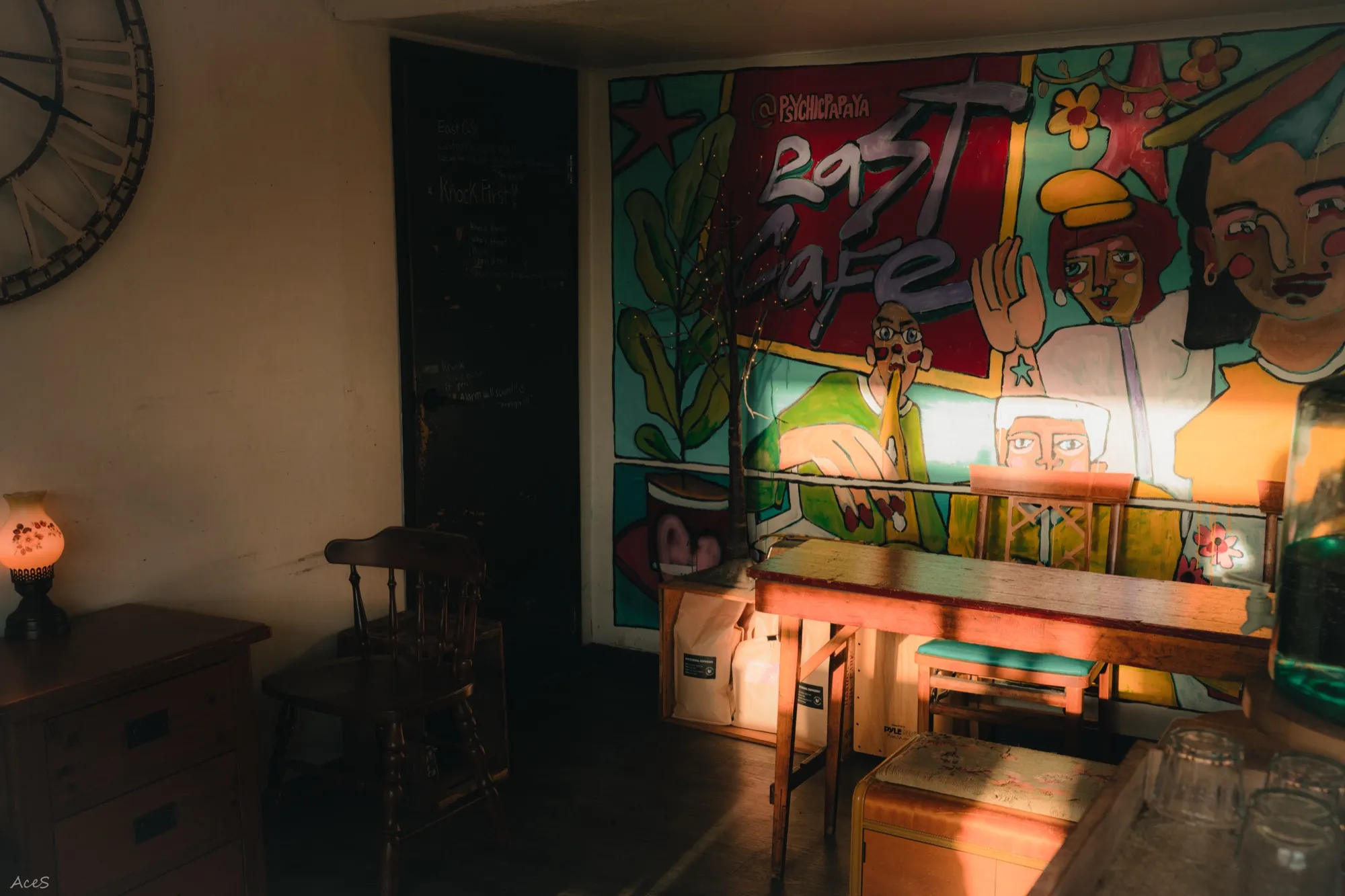 East Cafe interior with colorful mural wall art and vintage furniture in warm light