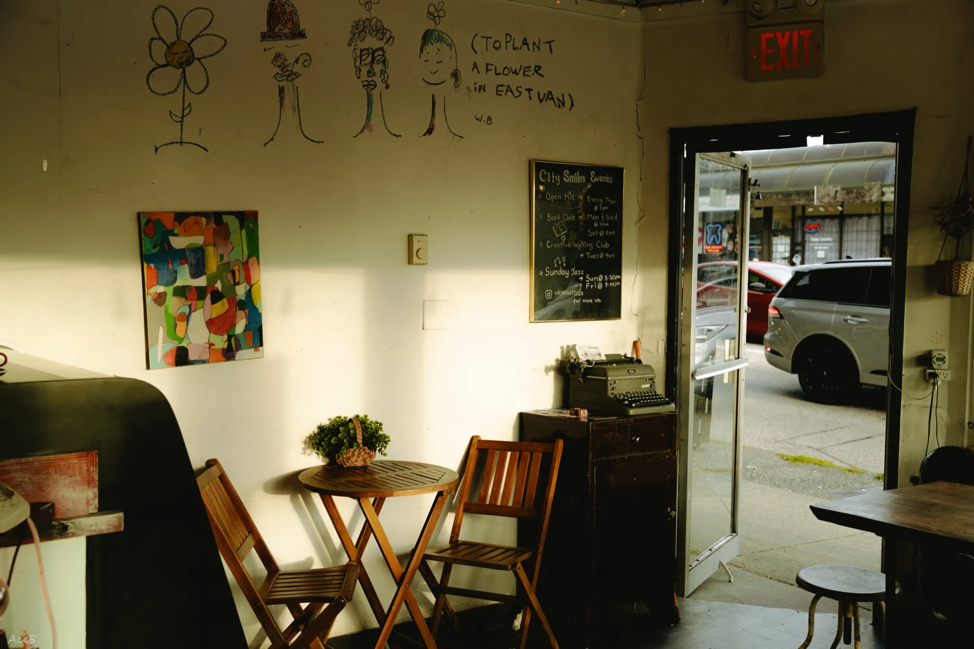 Eclectic cafe interior with wall art, chalkboard event board, and wooden folding chairs
