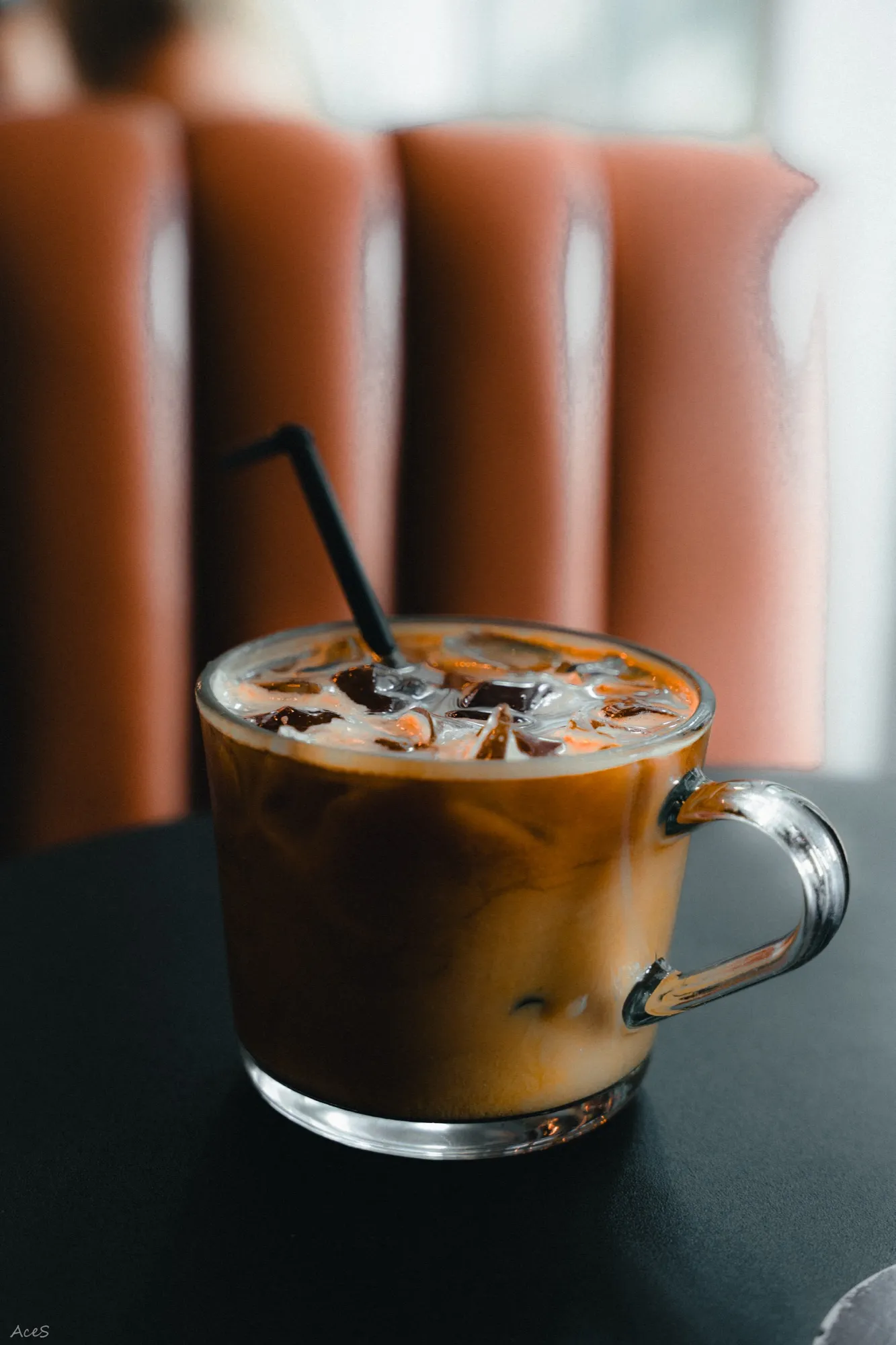 Iced coffee with cream swirl in glass mug with warm bokeh background